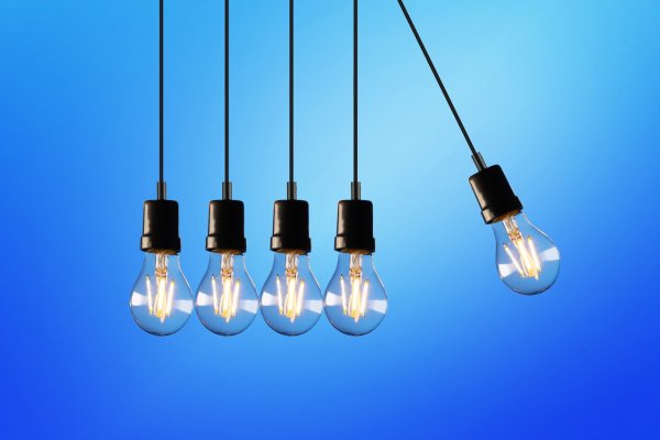 lightbulbs with the power turned on to them hanging down against a blue background